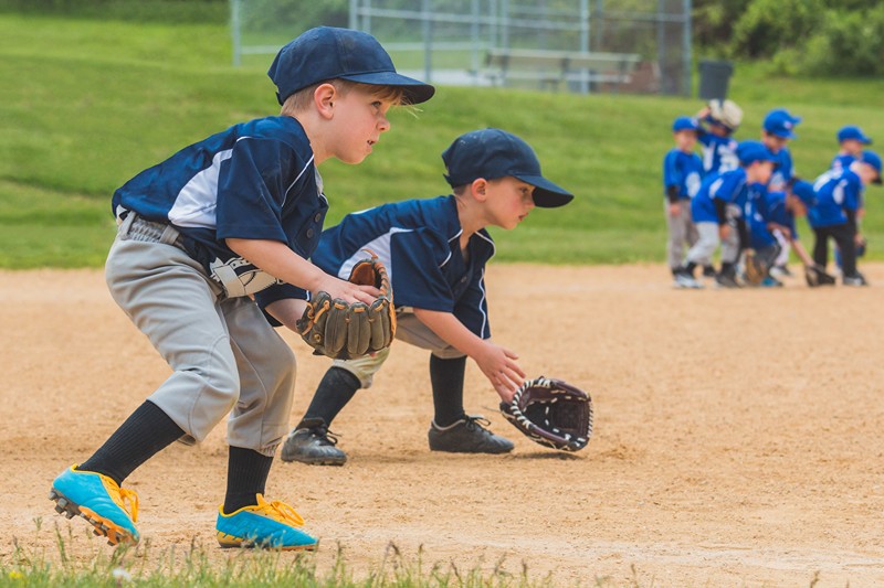 Two boys poised with gloves in little league baseball game.