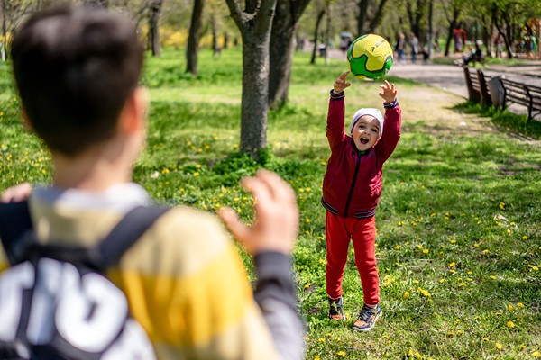 Little boy throwing large ball to big brother.