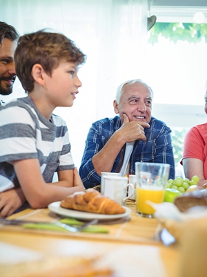 Young teen boy engaging on conversation at family dinner table.