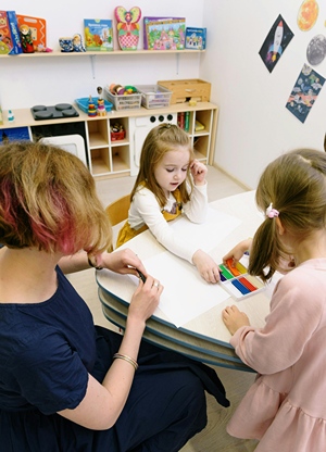 Young children working at a table with teacher in school.