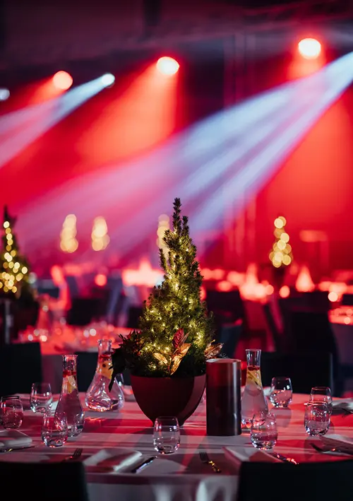 A Christmas tree table centerpiece on a table in a directories banquet room.