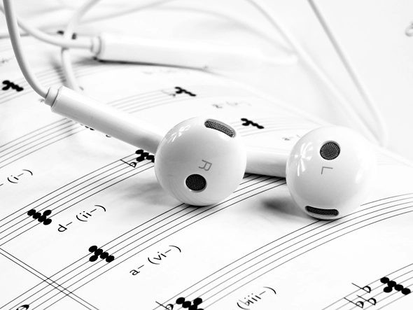White earphones laying on sheet music.