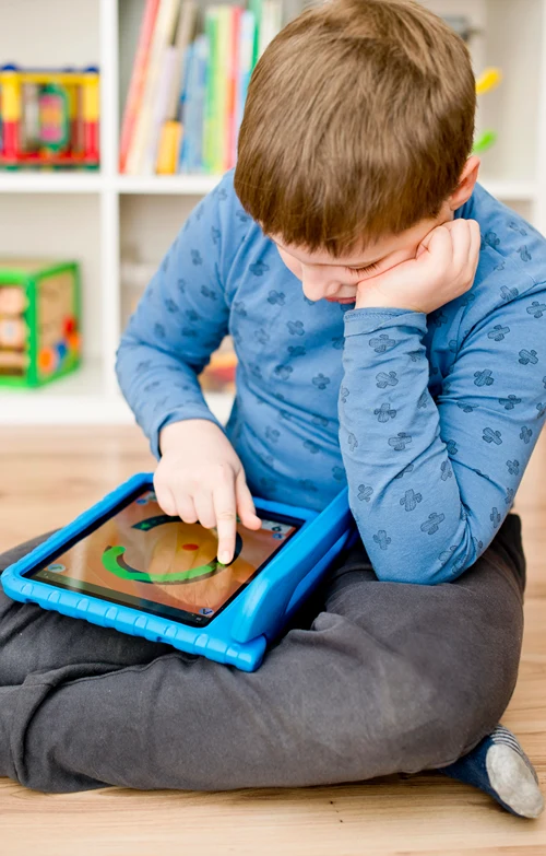 Autistic boy doing a learning exercise on a tablet.