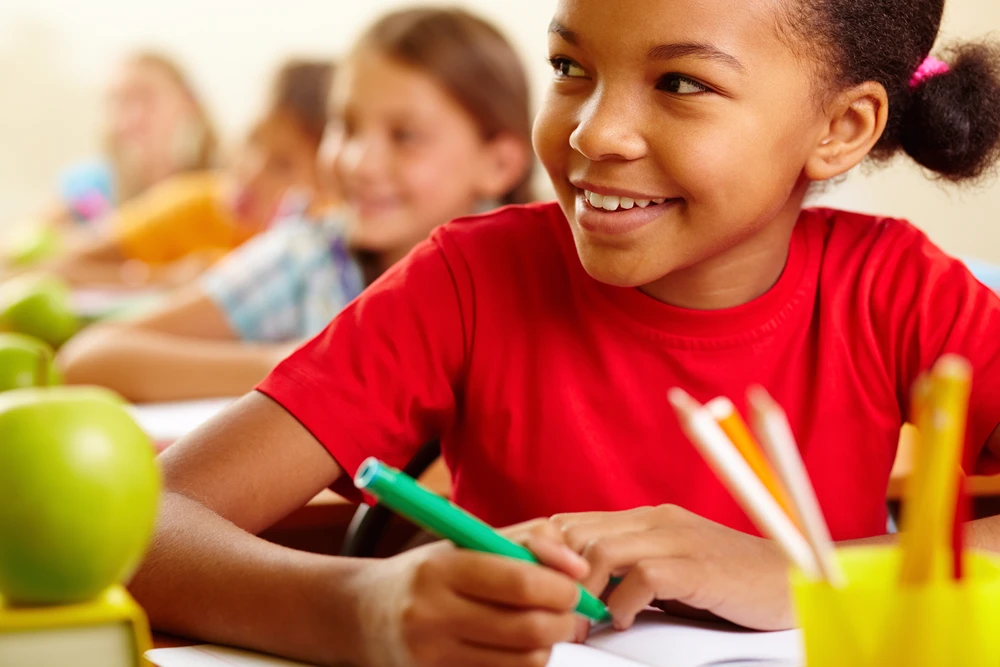 Girl smiling while working in at her desk in school.