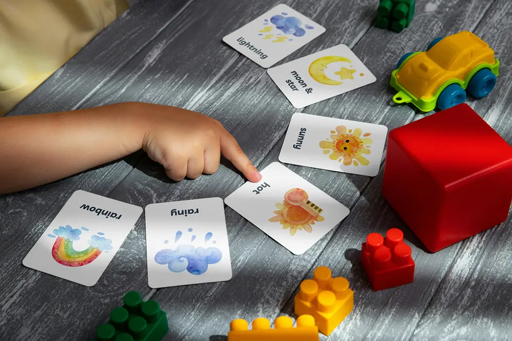 Flash cards laid out on a table will child points at one of them.