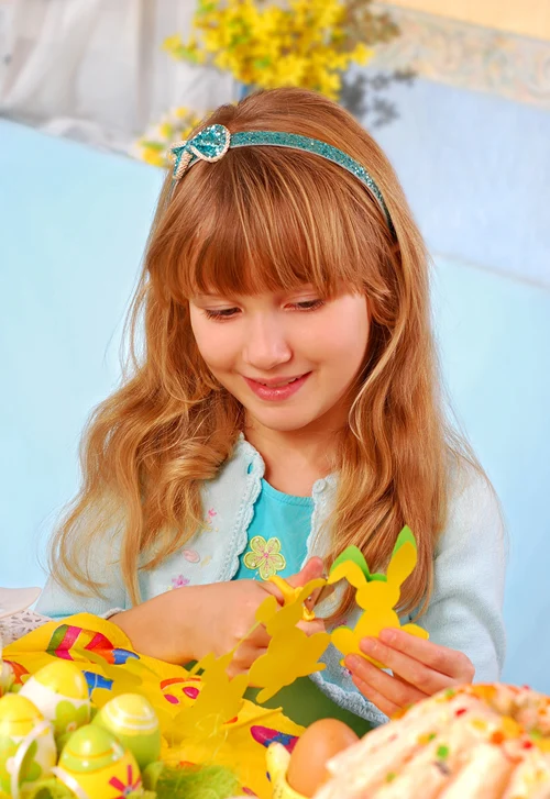 Girl cutting out Easter bunnies with scissors.