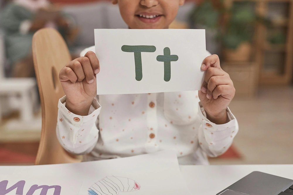 Girl holding up flashcard with an upper and lower care letter on it.