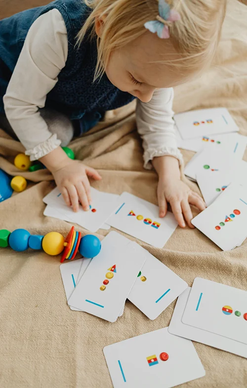 A little girl plays on the floor with an assortment of flash cards