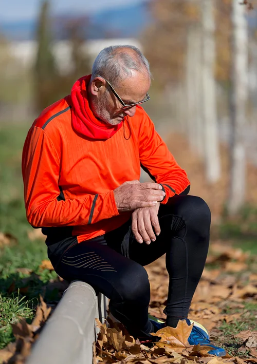 Senior takes a break from jogging and looks at his smart watch.