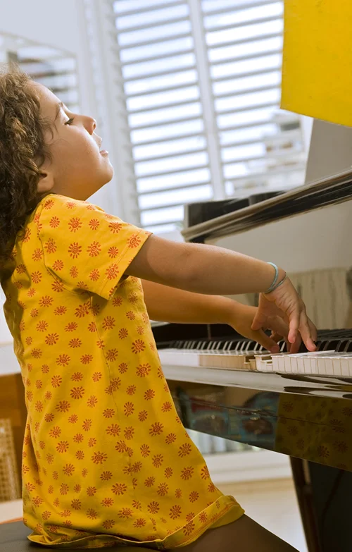 Young girl plays the piano with passion and vigor.
