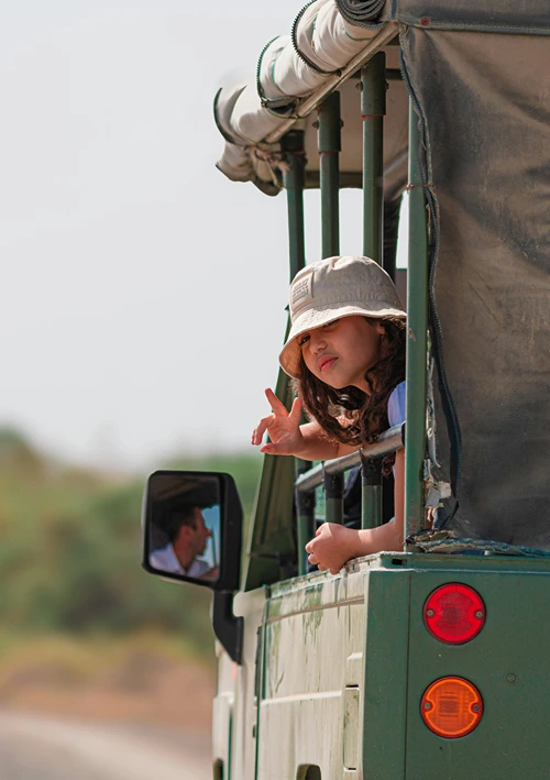 A young girl looking out the side of a safari vehicle.