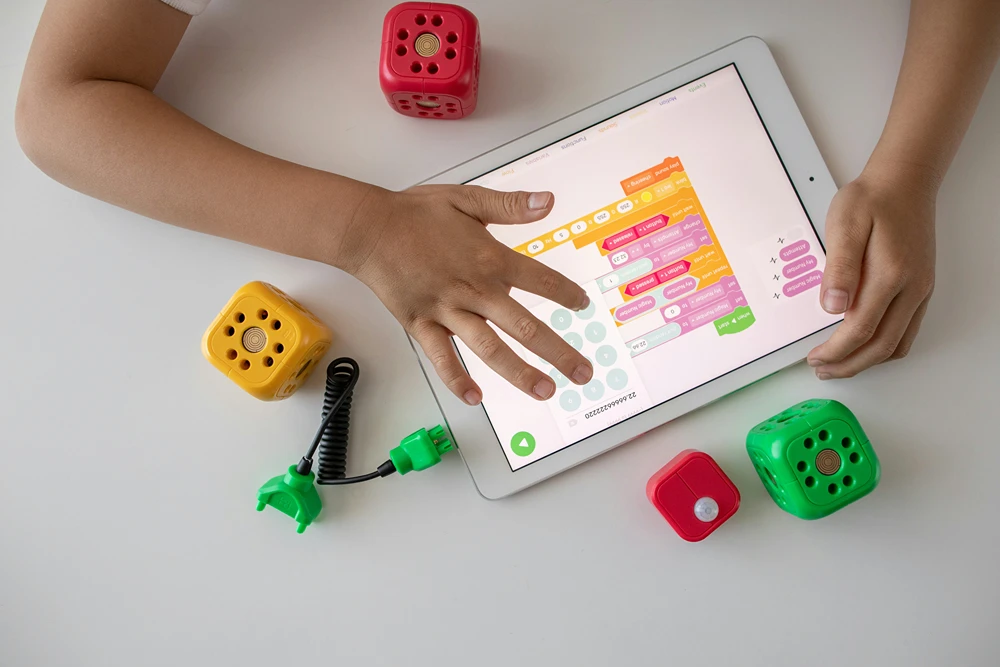 View from above of a child working on a tablet while seated at a table.