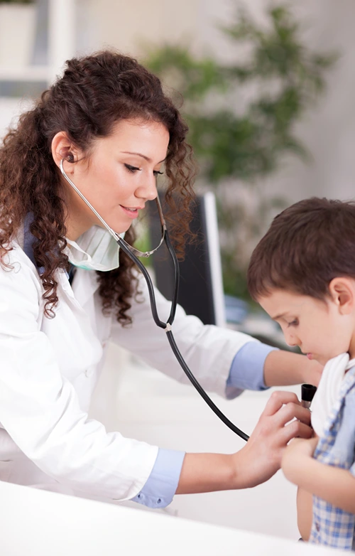 A female nurse practitioner checks little boys chest with a stethoscope.