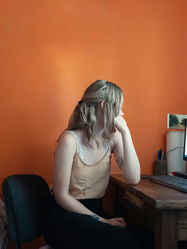 A young woman sits at a desk and waits for her slow computer.