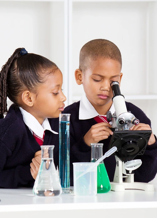 A girl and boy using a microscope at school.