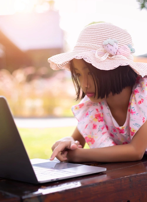 Young girl outdoors in sunny day online with laptop.