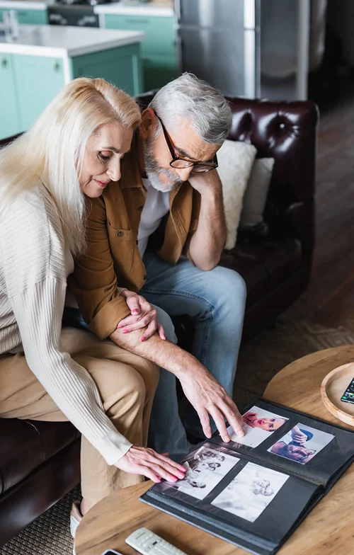 An hold couple seated together and looking at a memory book