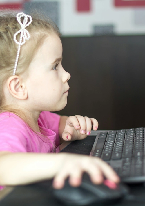 Girl using mouse and playing on desktop computer.