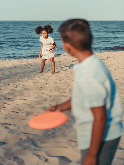 Boy throwing Frisbee to girl on a beach.