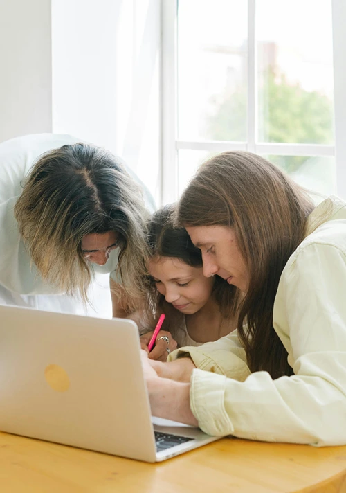 Parents researching with their child on a lap top.