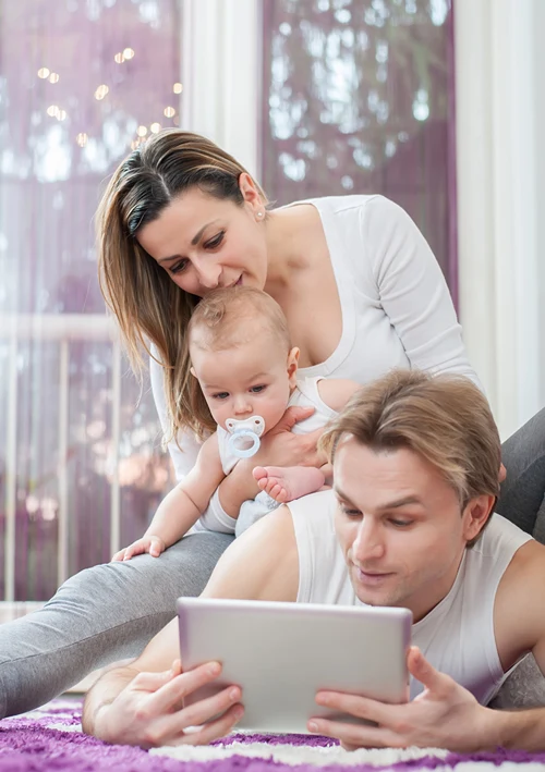 Dad looking at tablet as mom hold's baby.