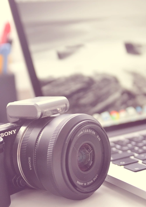 A camera on table next to a laptop.