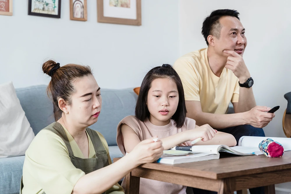 Teen and parents with books on coffee table in the living room.