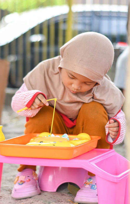 A small child is playing with a fishing play set.