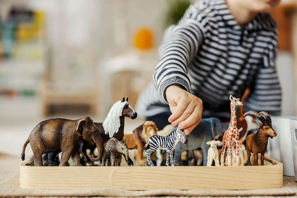 Child playing with miniature animals.