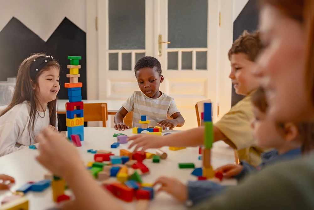 A group of kids sitting at a table playing with blocks.