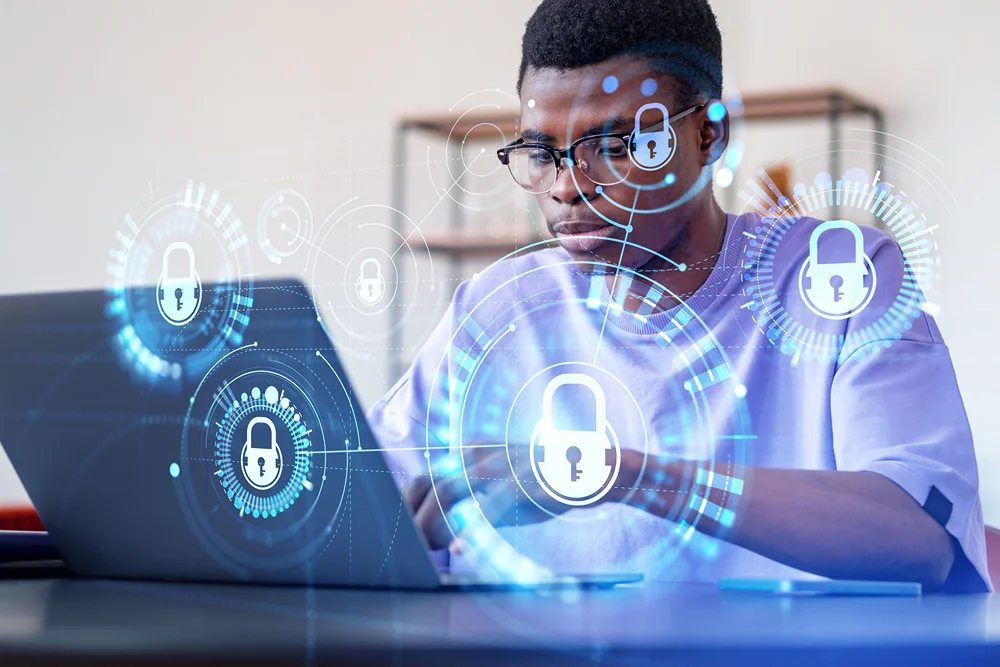 Student using laptop with cybersecurity imagery laid superimposed over top.