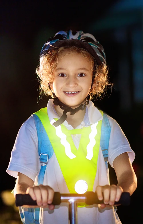 Boy wearing helmet and smiling on a scooter.