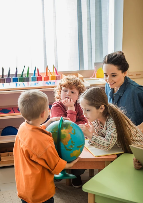 Children in kindergarten exploring a globe.