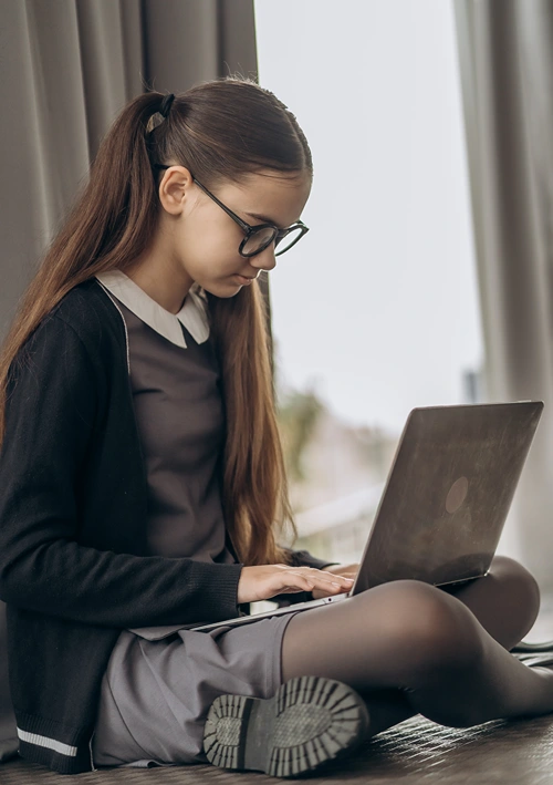 Nicely dressed middle school girl doing cyber school on lap top.