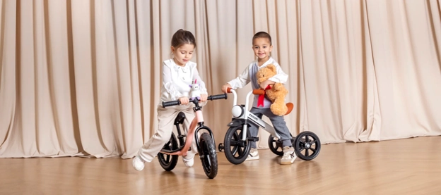A girl on a bike and boy on a tricycle.