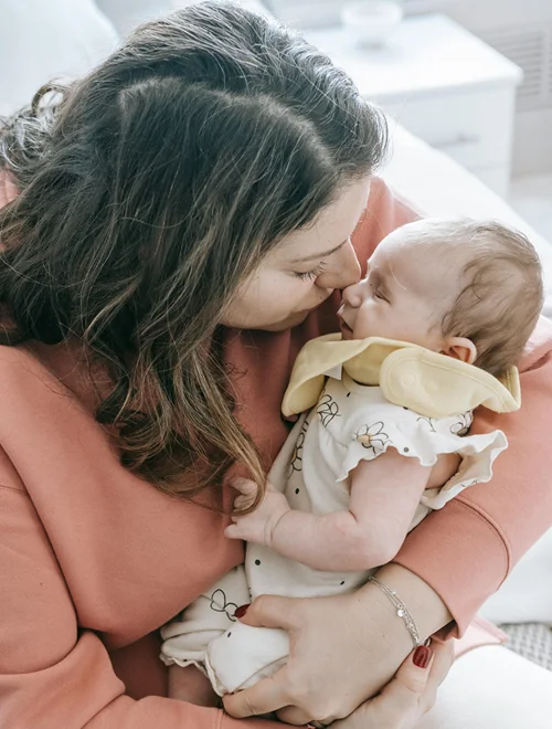 Mom holds her baby close as their nosed touch.