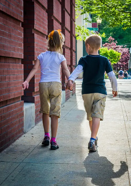 Girl and boy holding hands and walking.