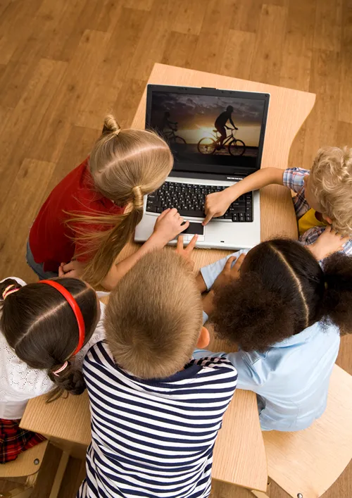 A small group of kids watching a video on a laptop.