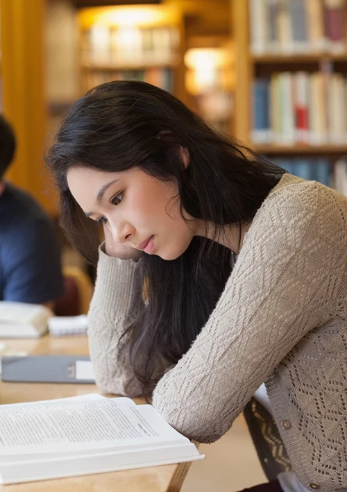 Female student intently studying in library.