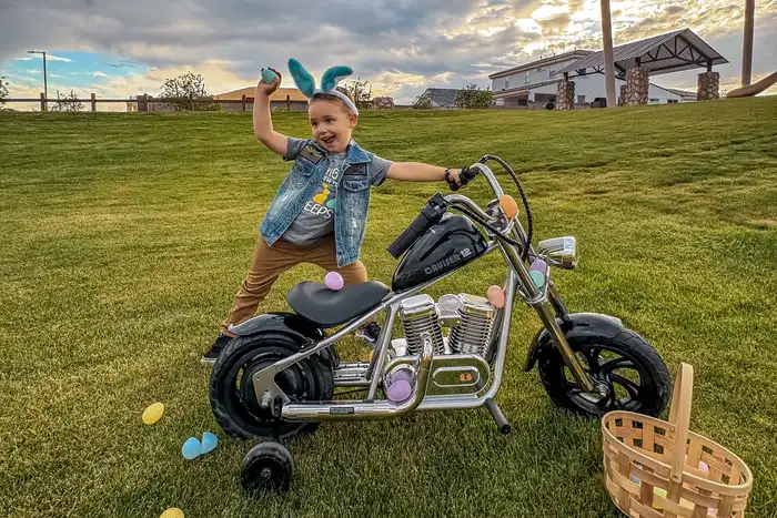 A middle schooled aged girl is posing on a mini-motorcycle.