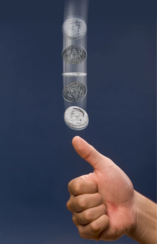 A hand flips a coin in the air.