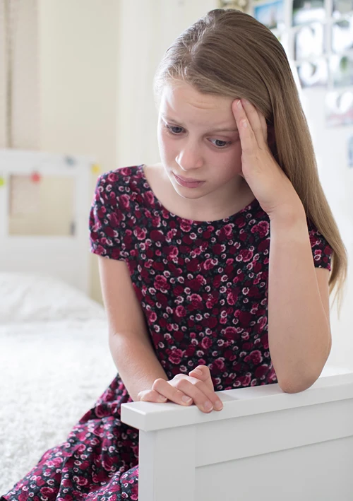 A middle school aged girl looking troubled.