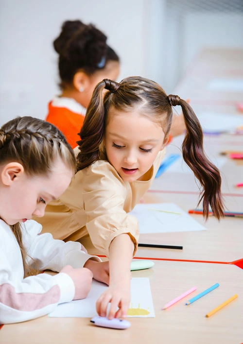 Elementary school girls coloring in class.