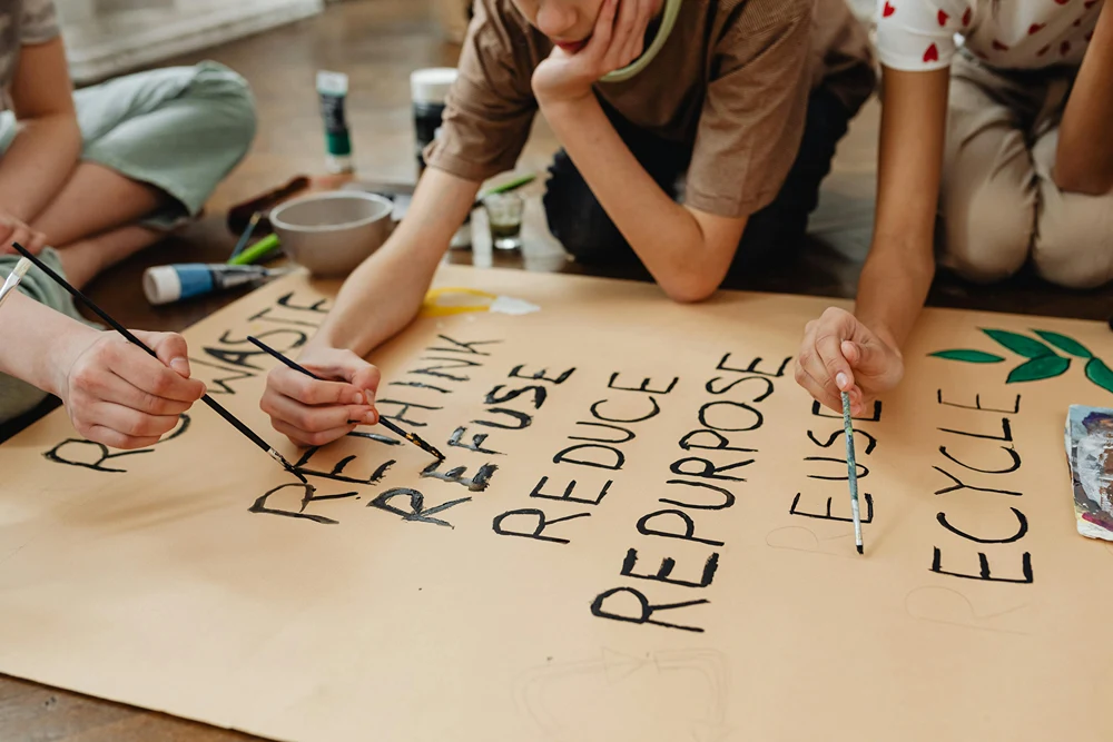 A group of kids create a large eco awareness poster.