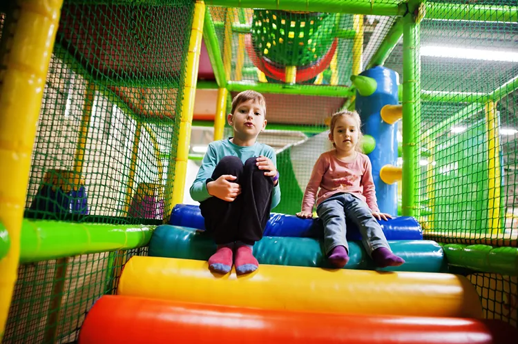 Girl and boy sitting together on indoor play equipment.