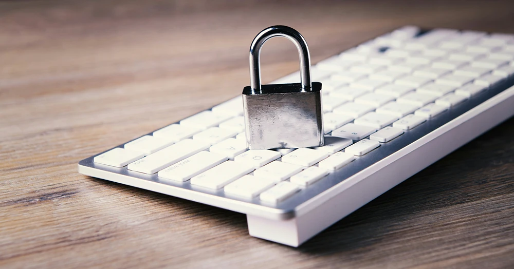 A traditional steel pad lock sits on a mac keyboard.