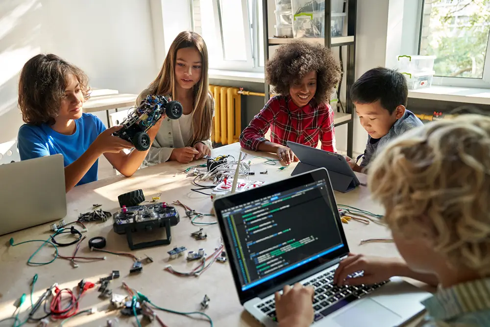 A group of kids at a tabled working on a tech project in class.