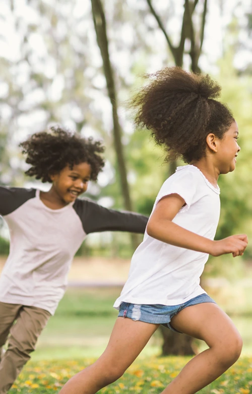 Two African American girl running faster outdoors.