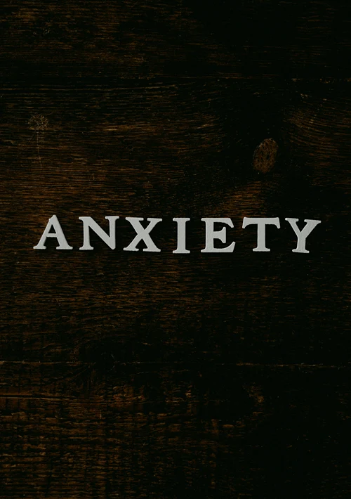 Letters placed on a wooden table spelling out the word Anxiety.
