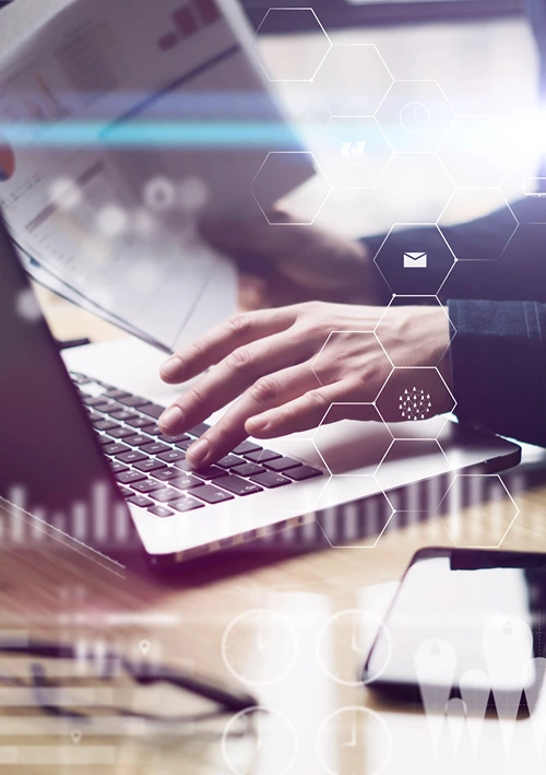 Male hand type on laptop while the other holds a paper report.